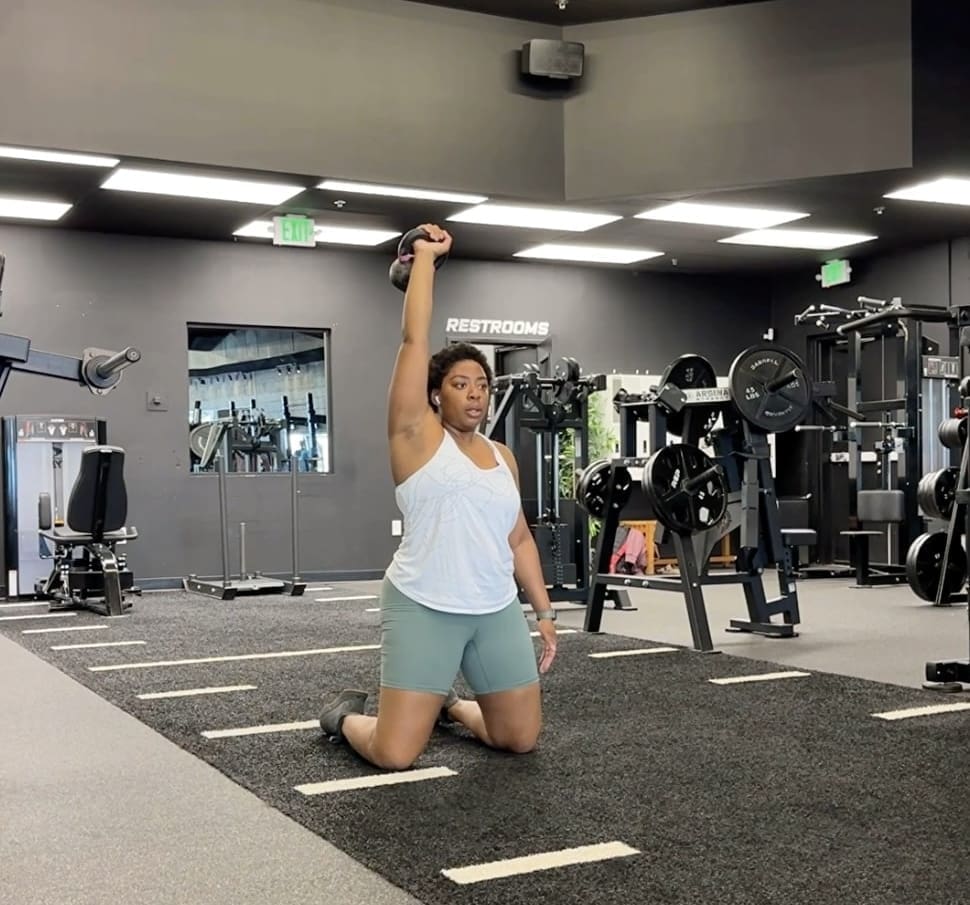 Woman in the gym in Denver, CO performing an overhead kettlebell exercise to help work on shoulder pain